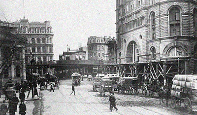 Black and white photo of an old city with horse drawn carriages.