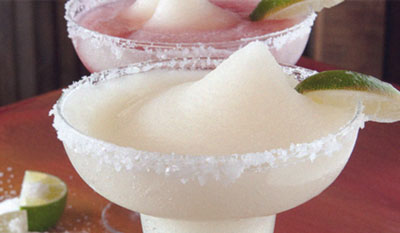 Two frozen margaritas with salt and lime, one plain and one with a pink swirl.