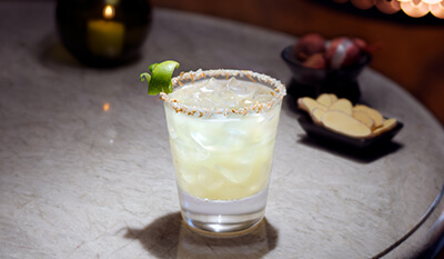 Cocktail with a salt rim and lime garnish on a table.