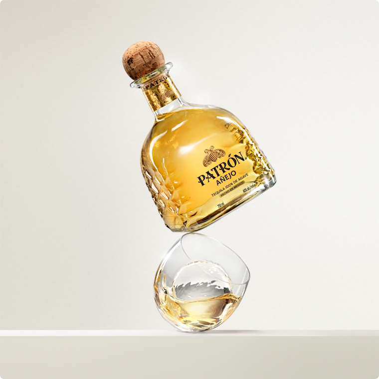 Patrón Añejo Tequila bottle and cocktail with an orange twist.