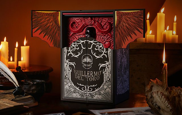 Box of Patrón X Guillermo del Toro tequila in a room with lit candles.